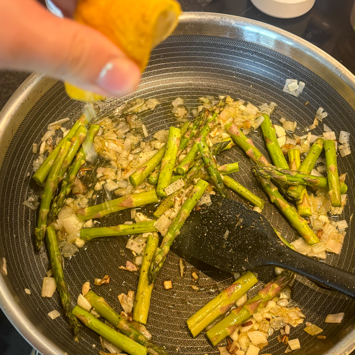 Adding fresh lemon juice to asparagus and shallots for beef and asparagus pasta in a skillet
