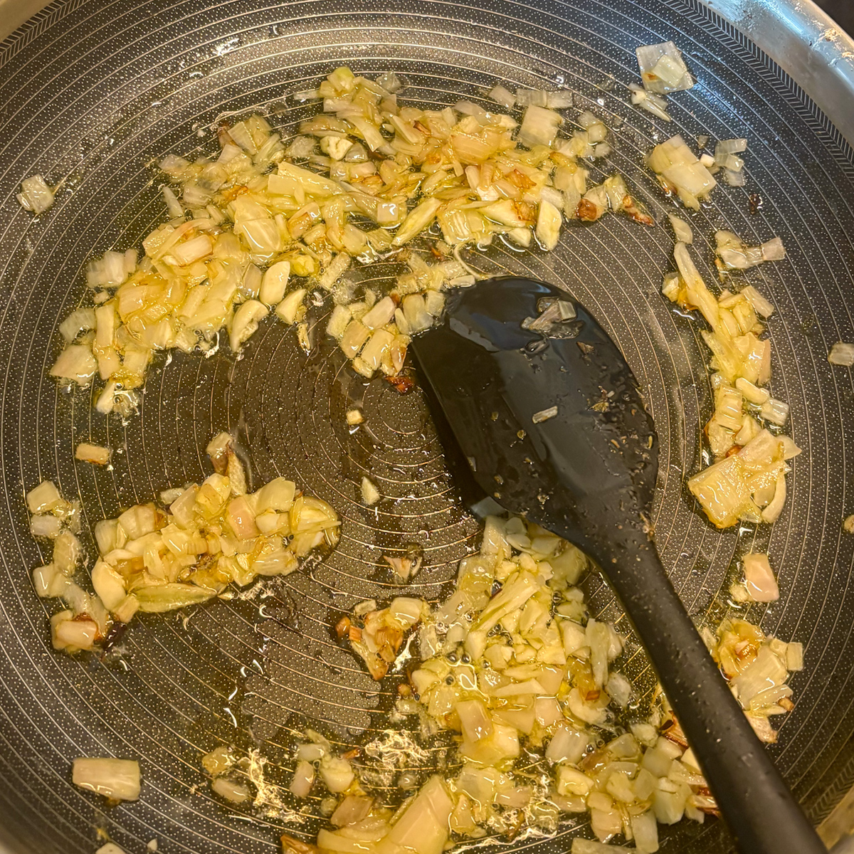 Sautéed shallots and garlic in olive oil for beef and asparagus pasta in a non-stick pan
