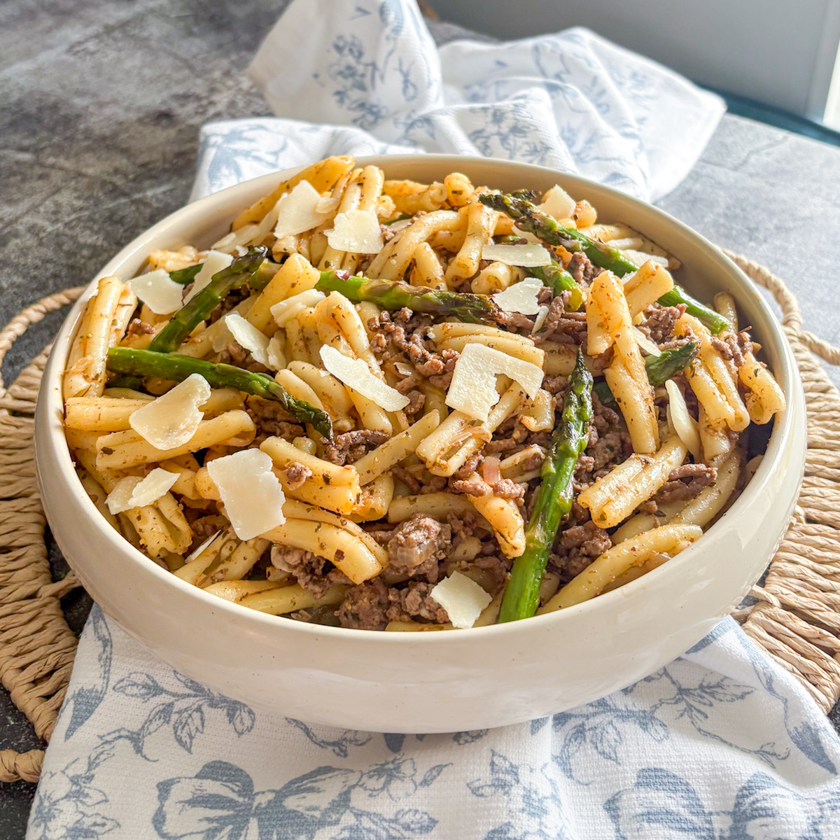 Bowl of beef and asparagus pasta with trecce, lean beef mince and fresh asparagus topped with shaved parmesan
