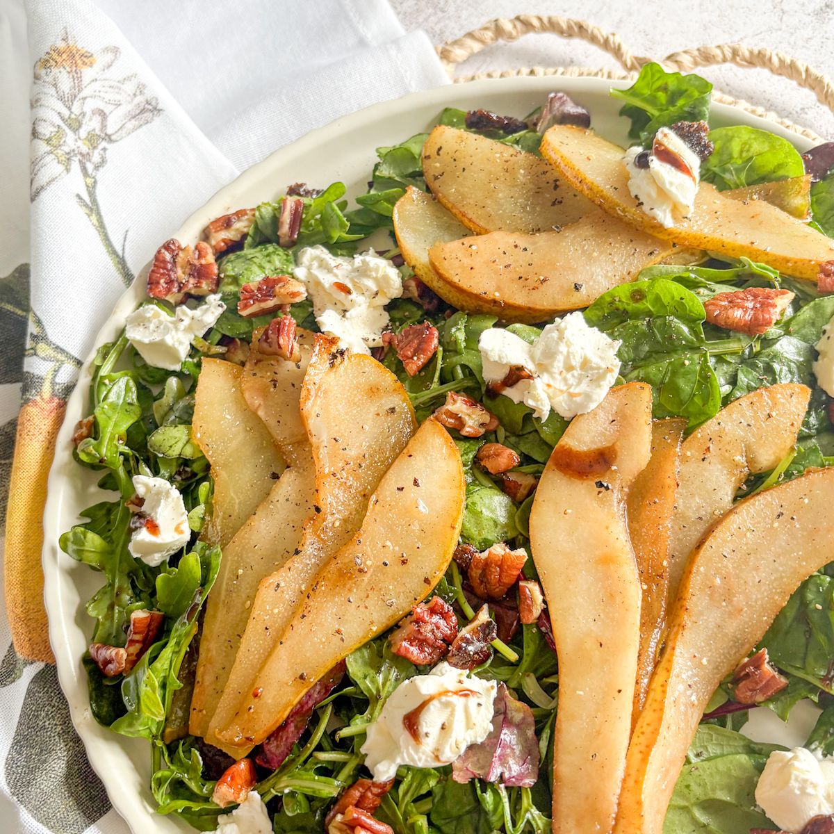 Close-up of caramelised pear salad with sliced golden pears, pecans and mascarpone dollops