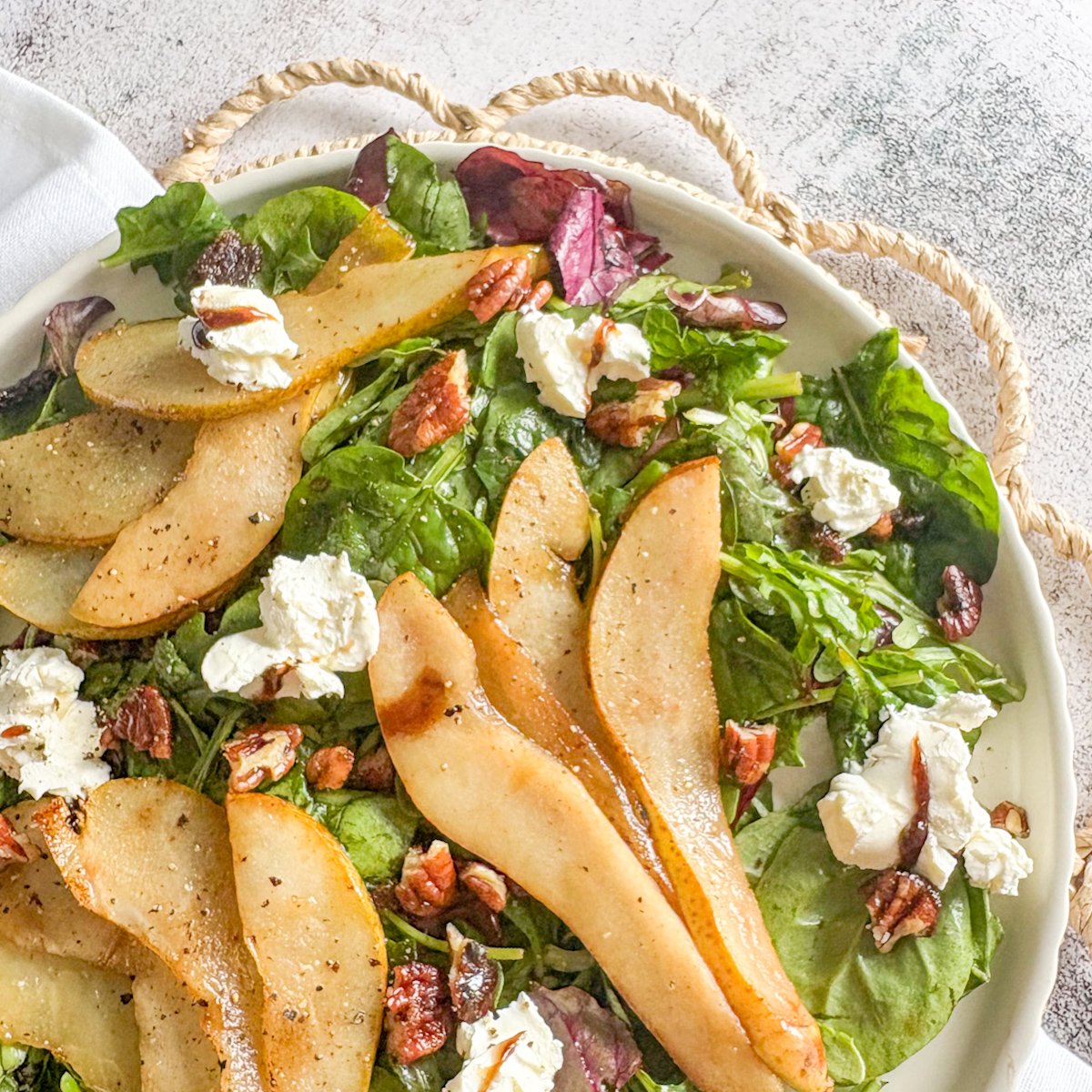Caramelised pear salad plated with golden pears, mascarpone and pecans on mixed leaves