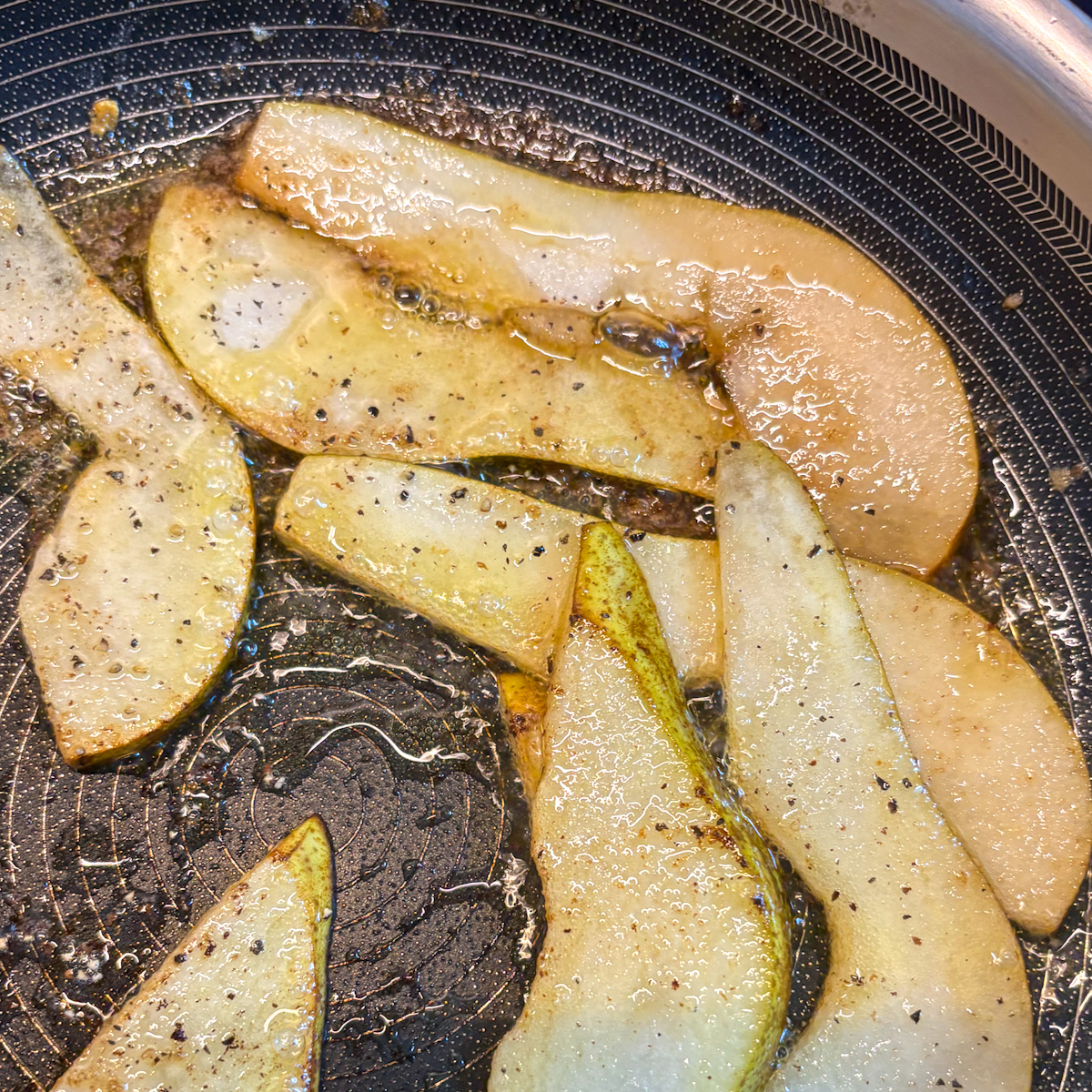 Pear slices frying in butter with black pepper, caramelising at the edges for caramelised pear salad