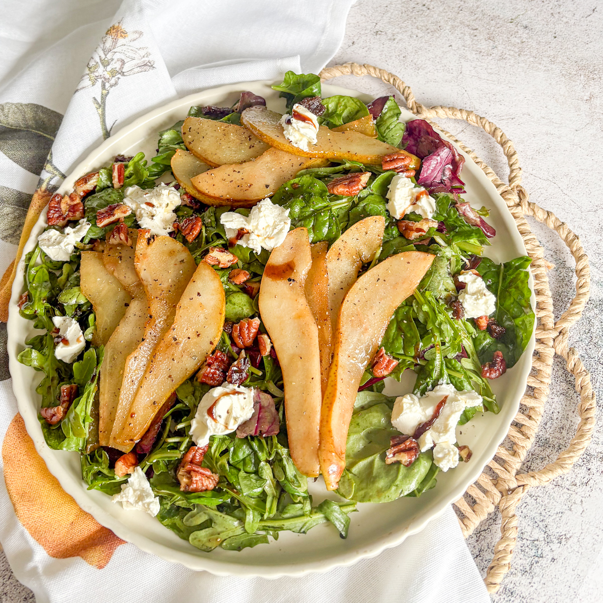 Overhead caramelised pear salad with pecans, mascarpone and balsamic glaze on mixed baby leaves