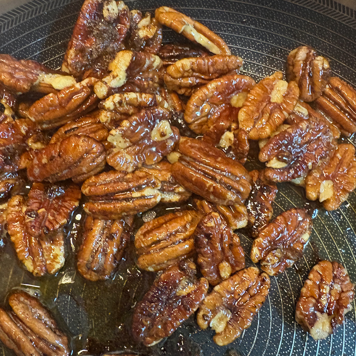 Caramelising pecans in a pan with brown sugar and butter for caramelised pear salad