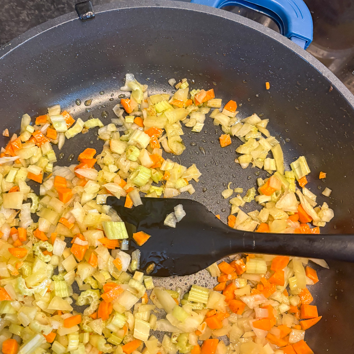 Diced onion, carrot and celery sautéing in a pan for dirty rice with beef mince