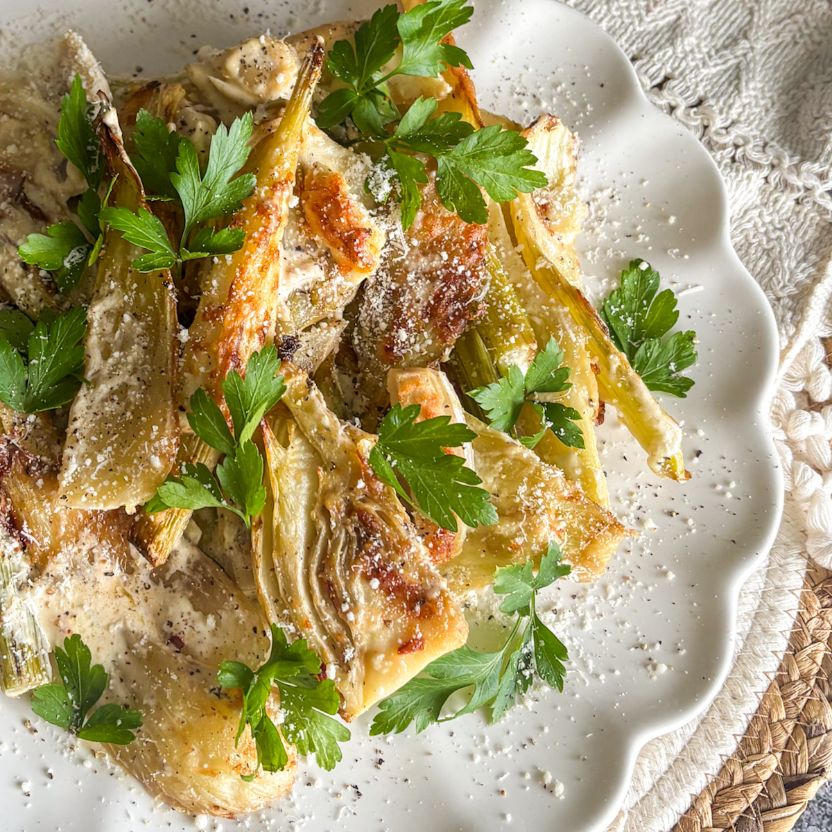 Oven baked fennel with parmesan on a scalloped white plate