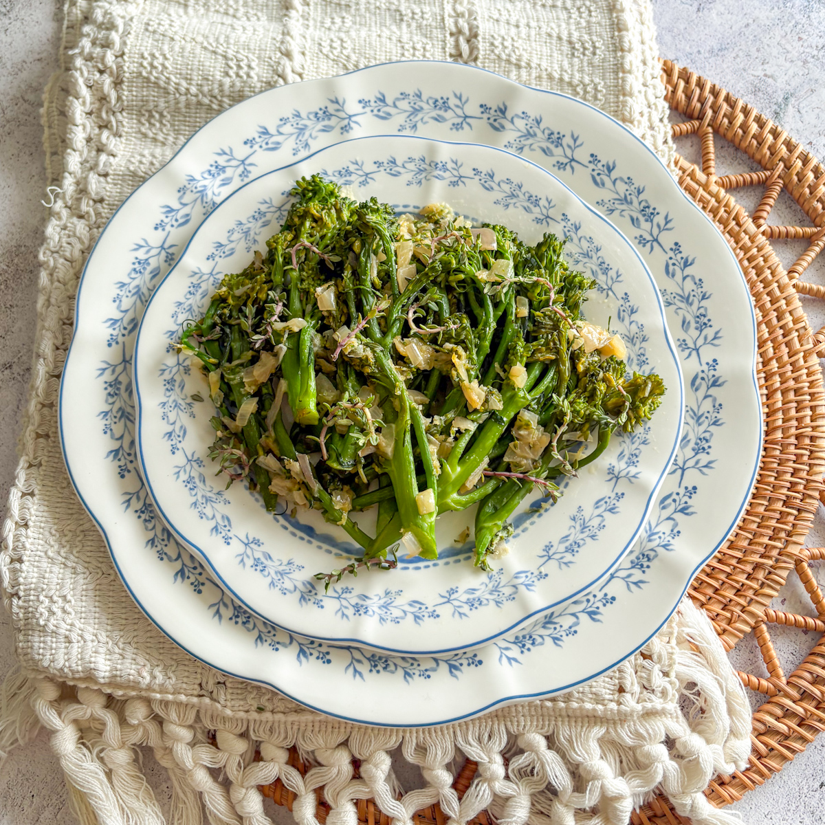 Overhead view of pan-steamed broccolini on a blue and white patterned plate