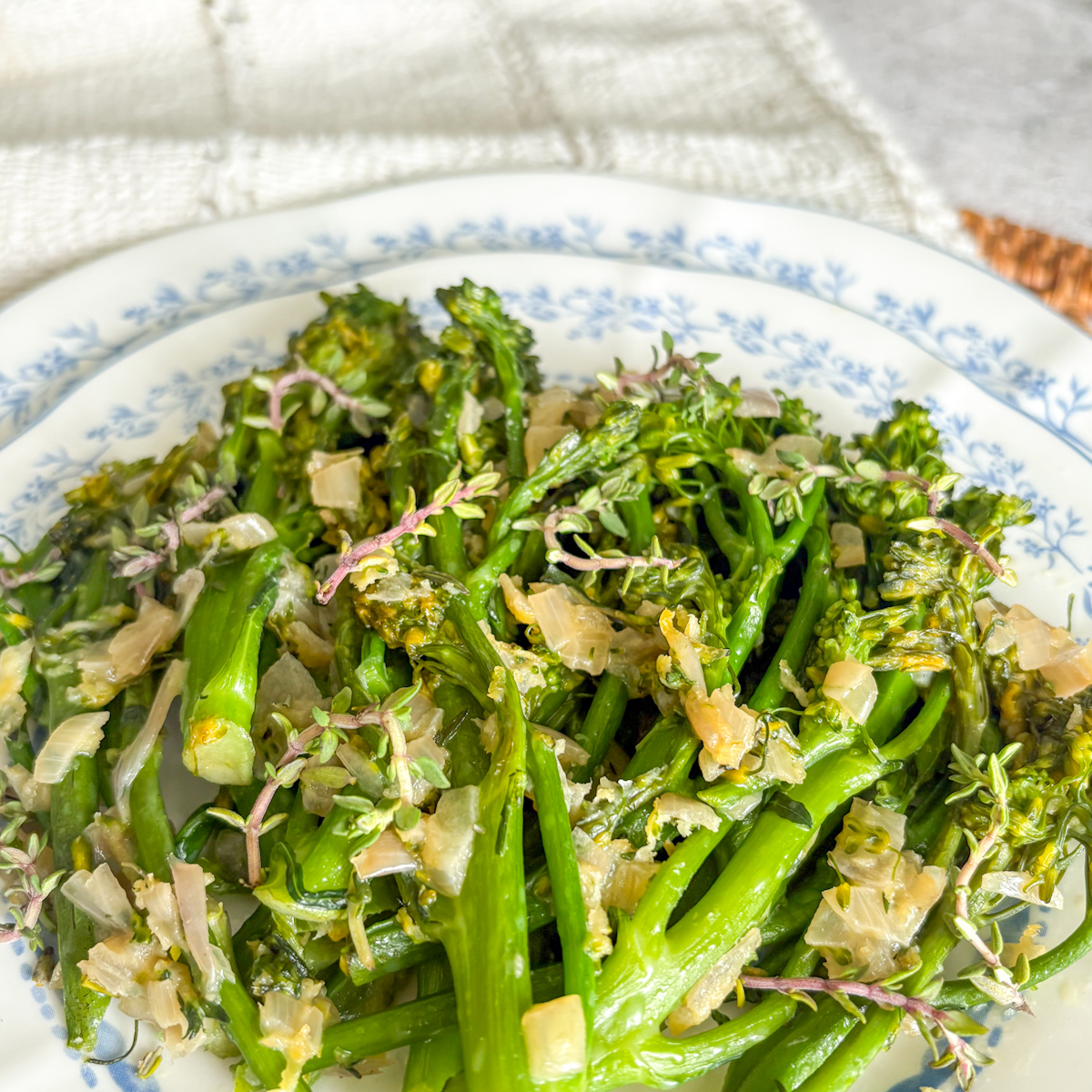 Close-up of pan-steamed broccolini topped with shallot, fresh thyme and lemon zest