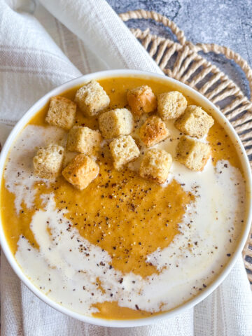 Creamy roasted root vegetable soup topped with golden croutons, double cream swirl and cracked black pepper