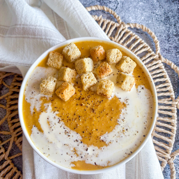 Creamy roasted root vegetable soup topped with golden croutons, double cream swirl and cracked black pepper