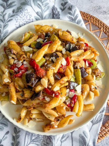 Hearty plate of roasted vegetable pasta with courgette, aubergine and peppers topped with parmesan