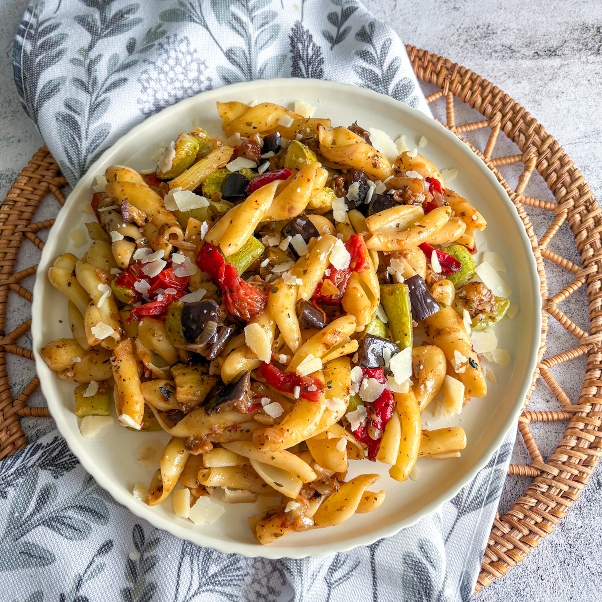 Hearty plate of roasted vegetable pasta with courgette, aubergine and peppers topped with parmesan
