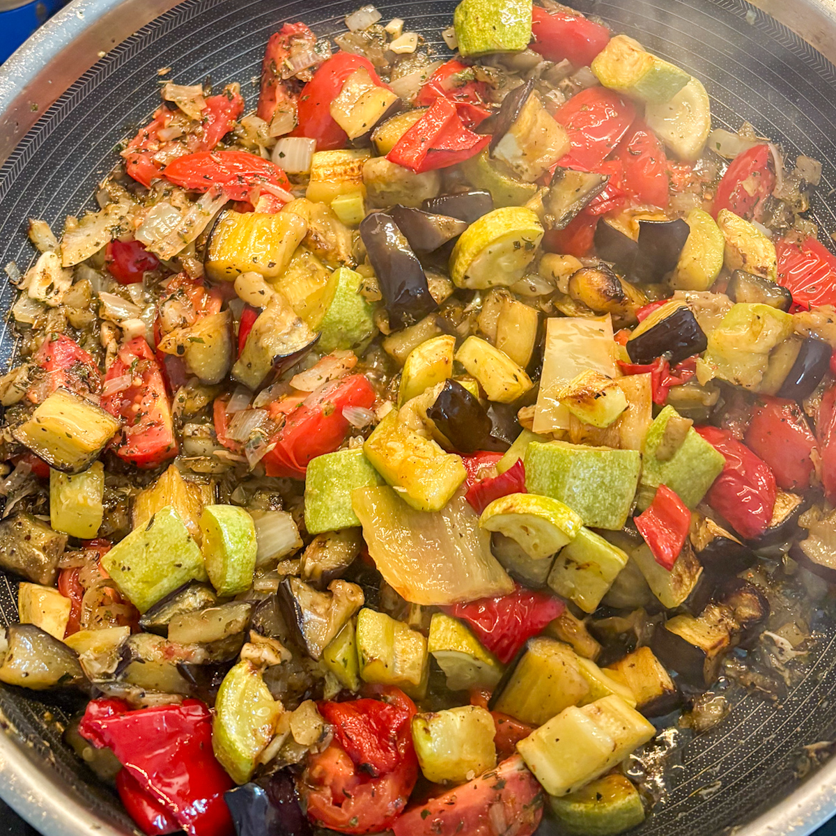 Roasted vegetables for roasted vegetable pasta cooking in a large skillet with onions and herbs