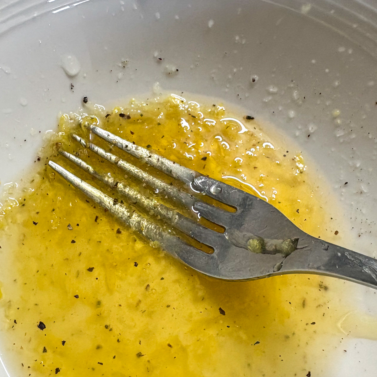Whisking silky honey lemon dressing for strawberry rocket salad with a fork