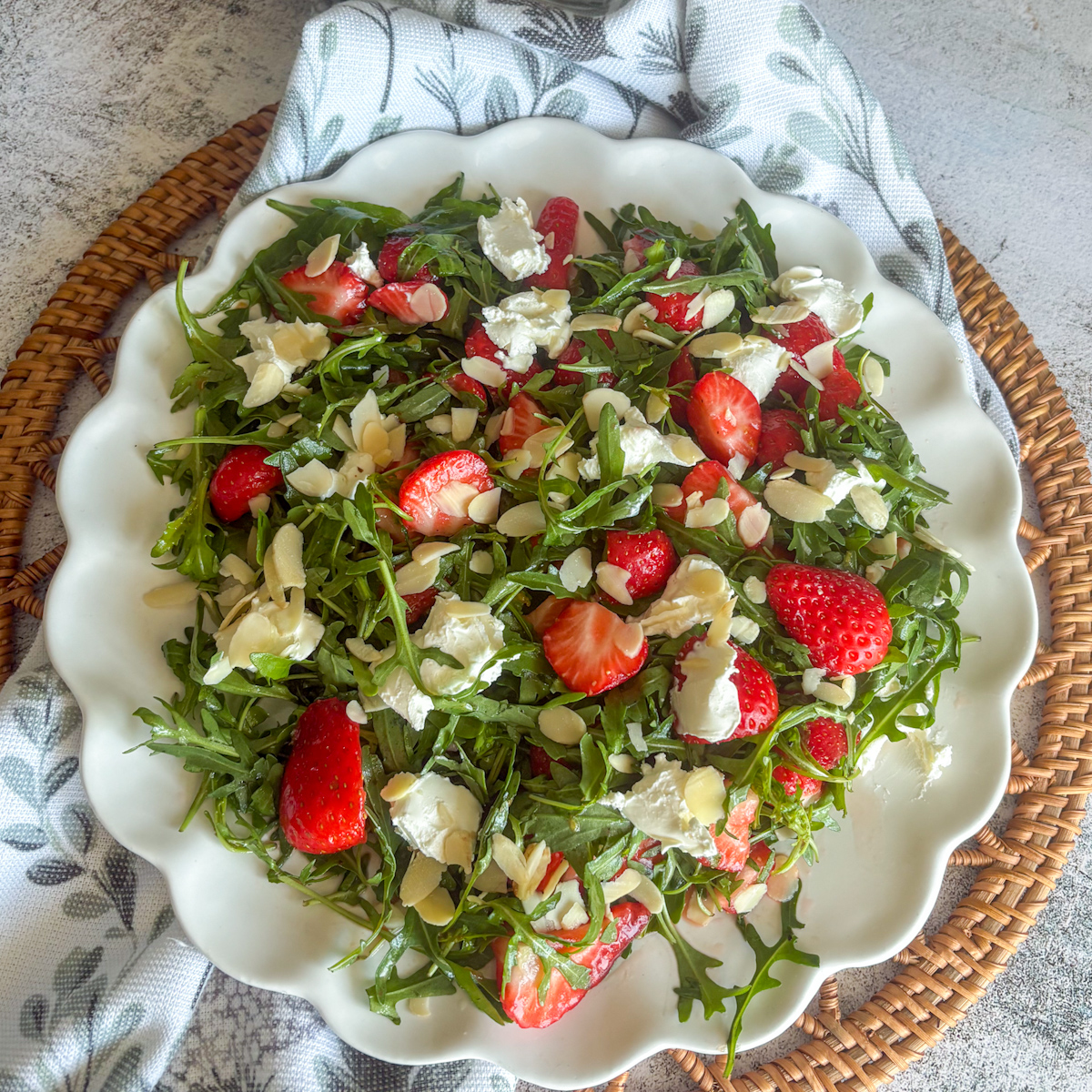 Strawberry rocket salad served on a white plate with mascarpone and flaked almonds