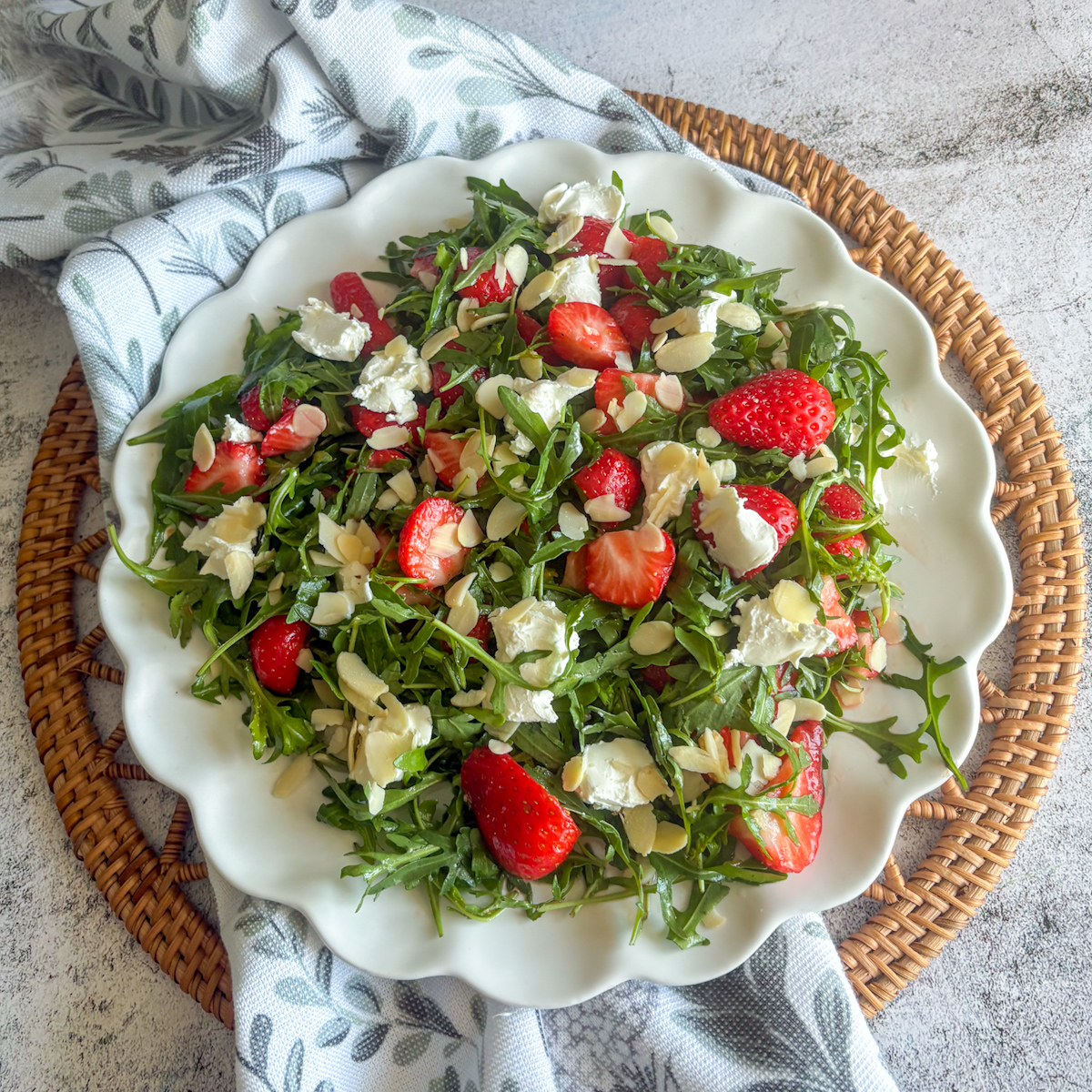 Overhead strawberry rocket salad on a scalloped plate with mascarpone and almonds