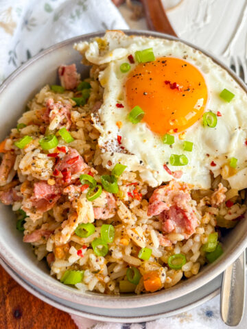 Breakfast dirty rice with crispy bacon and a runny fried egg topped with spring onions