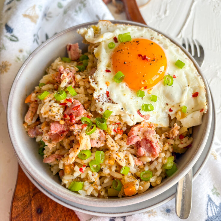 Breakfast dirty rice with crispy bacon and a runny fried egg topped with spring onions