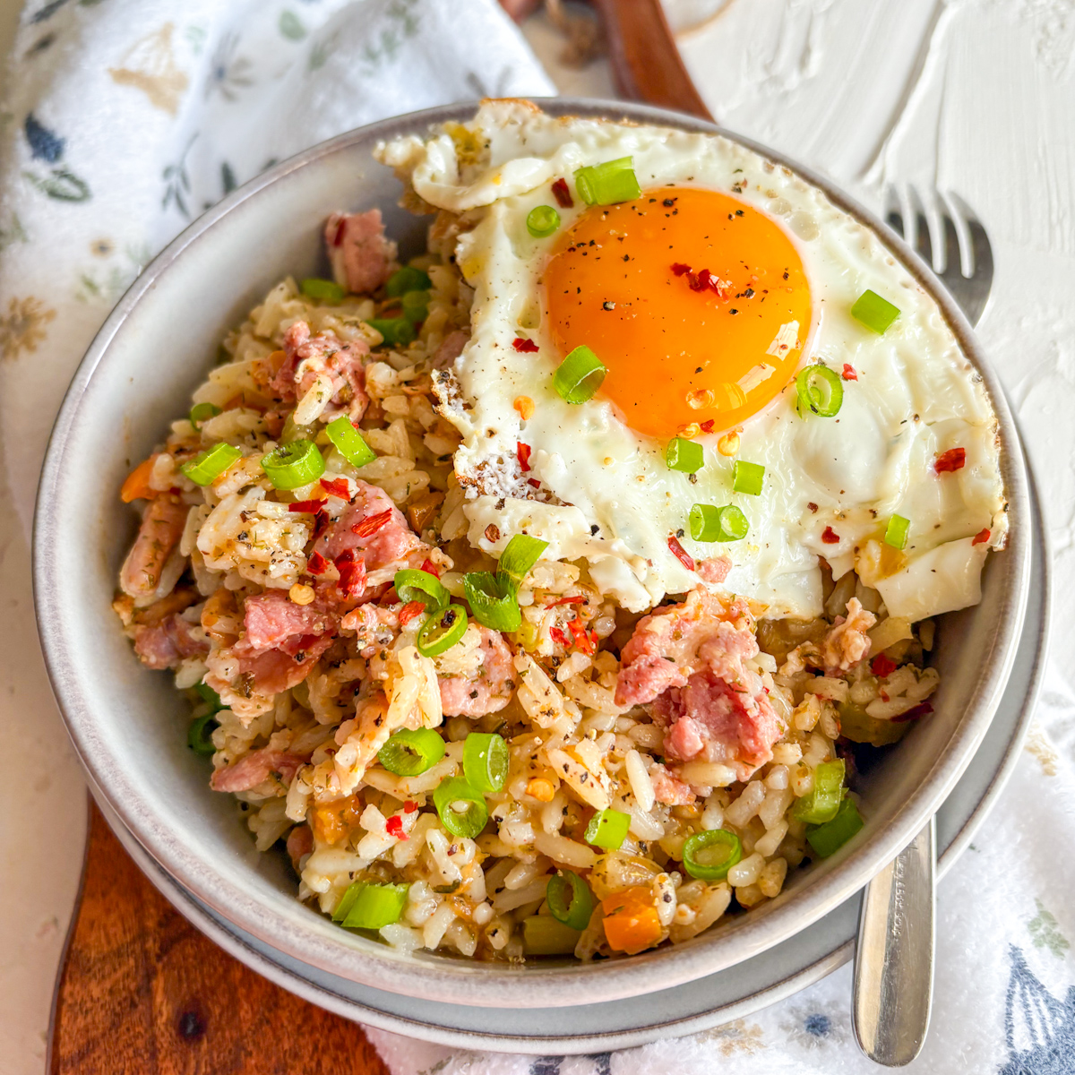 Breakfast dirty rice with crispy bacon and a runny fried egg topped with spring onions