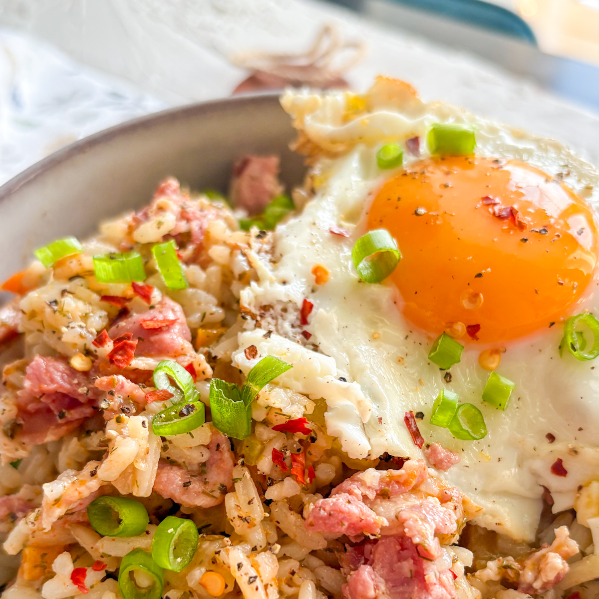 Close-up of breakfast dirty rice with runny fried egg and chilli flakes