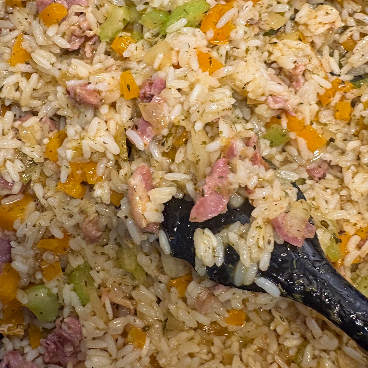 Breakfast dirty rice in the skillet with bacon, sweet pepper and celery