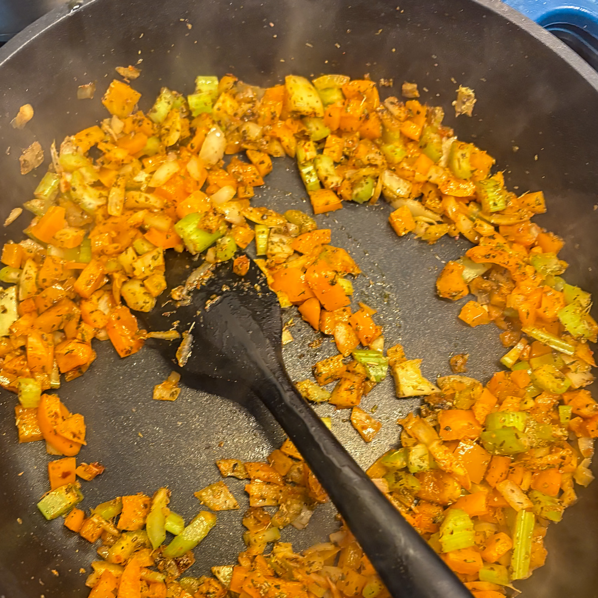 Charring veggies and spices for breakfast dirty rice in a black pan
