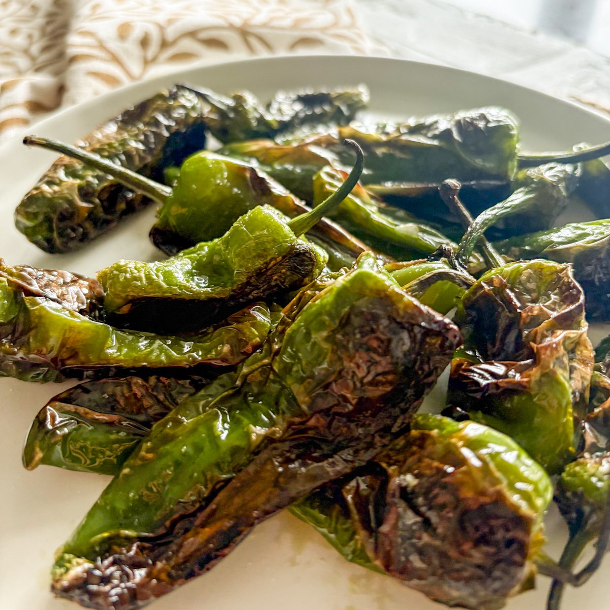 Close-up of blistered padron peppers showing soft charred skin