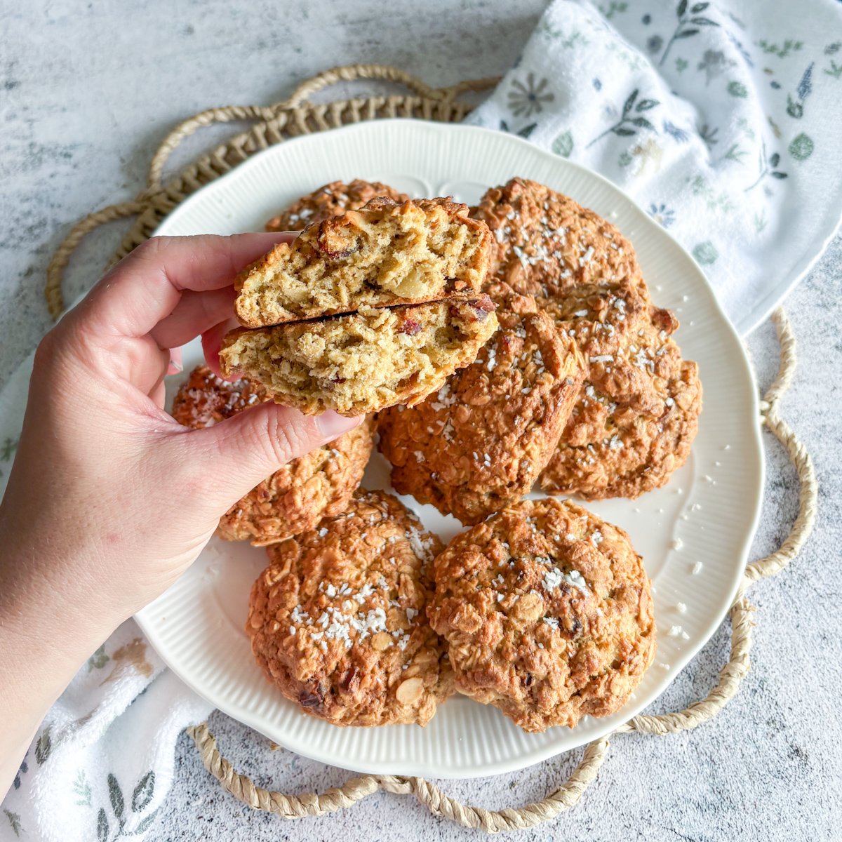 Hand holding a halved oatmeal cookie with dates showing the soft centre and date pieces