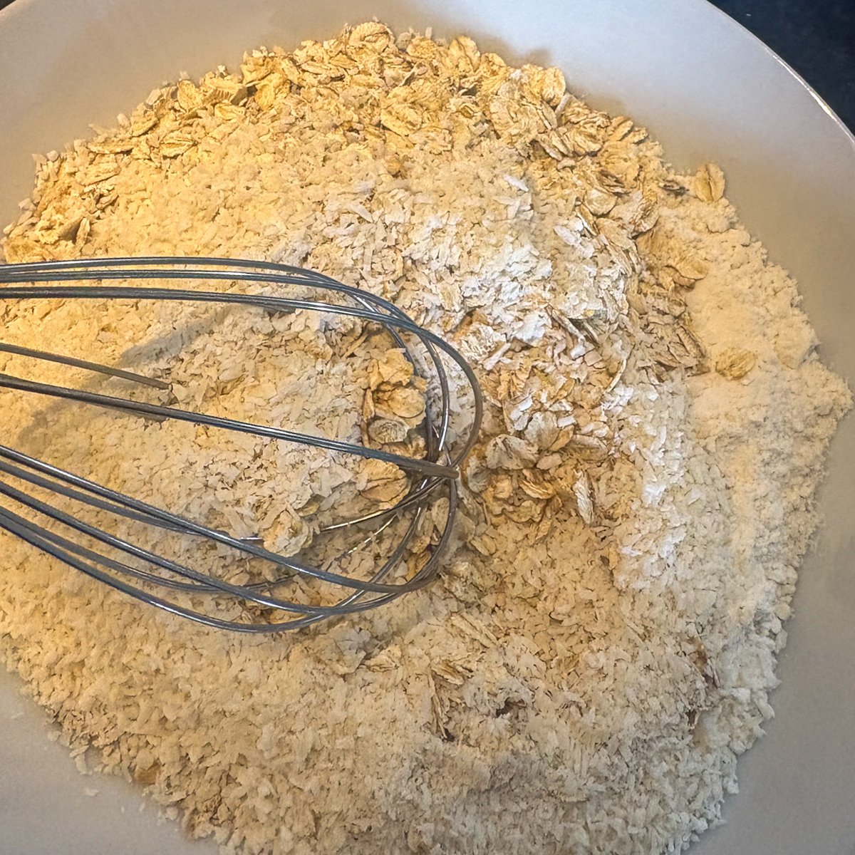 Dry ingredients for oatmeal cookies with dates — oats, flour and coconut whisked in a bowl