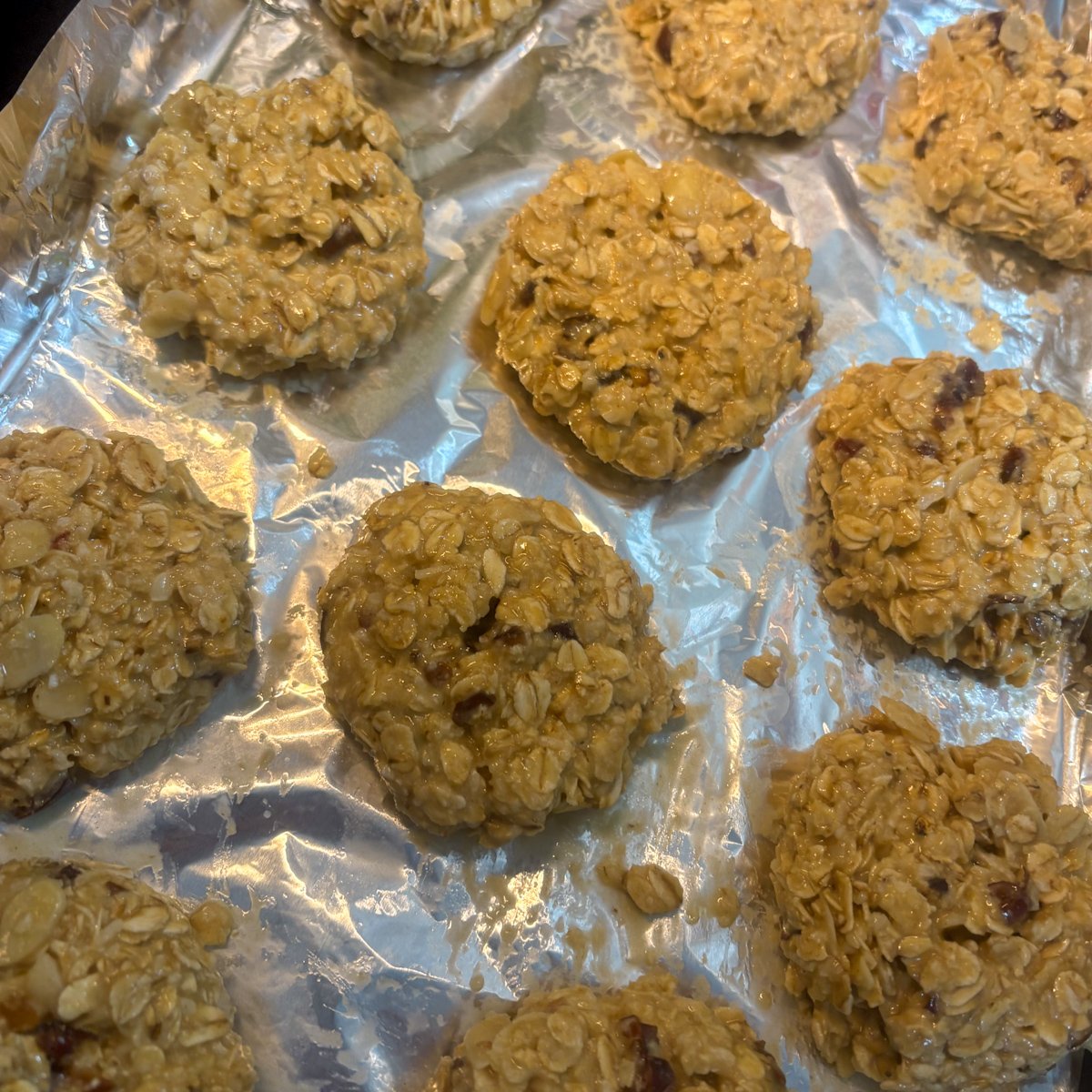 Unbaked oatmeal cookies with dates rolled into balls on a lined baking tray