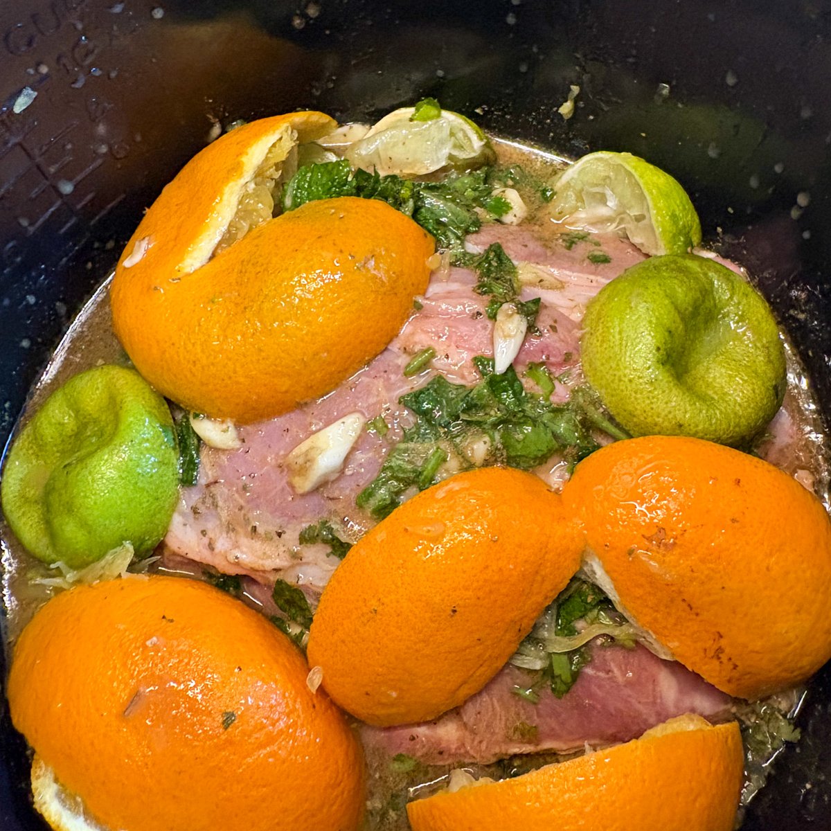 Mojo marinade pork with orange and lime peels in slow cooker