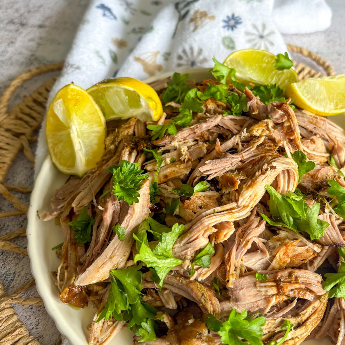 Juicy mojo pork recipe served on a cream plate with lime wedges and fresh coriander leaves