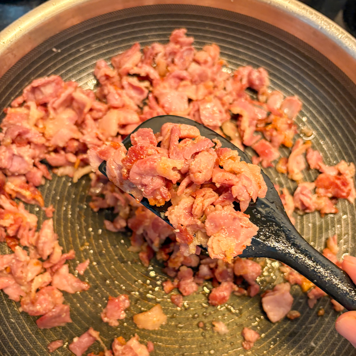 Crispy fried bacon offcuts on a spatula for breakfast burritos