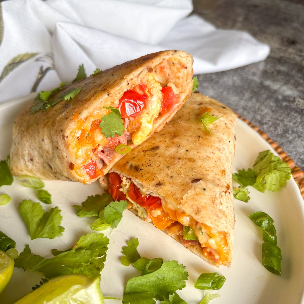 Close-up of a breakfast burrito filled with bacon, egg, pepper and melted cheddar