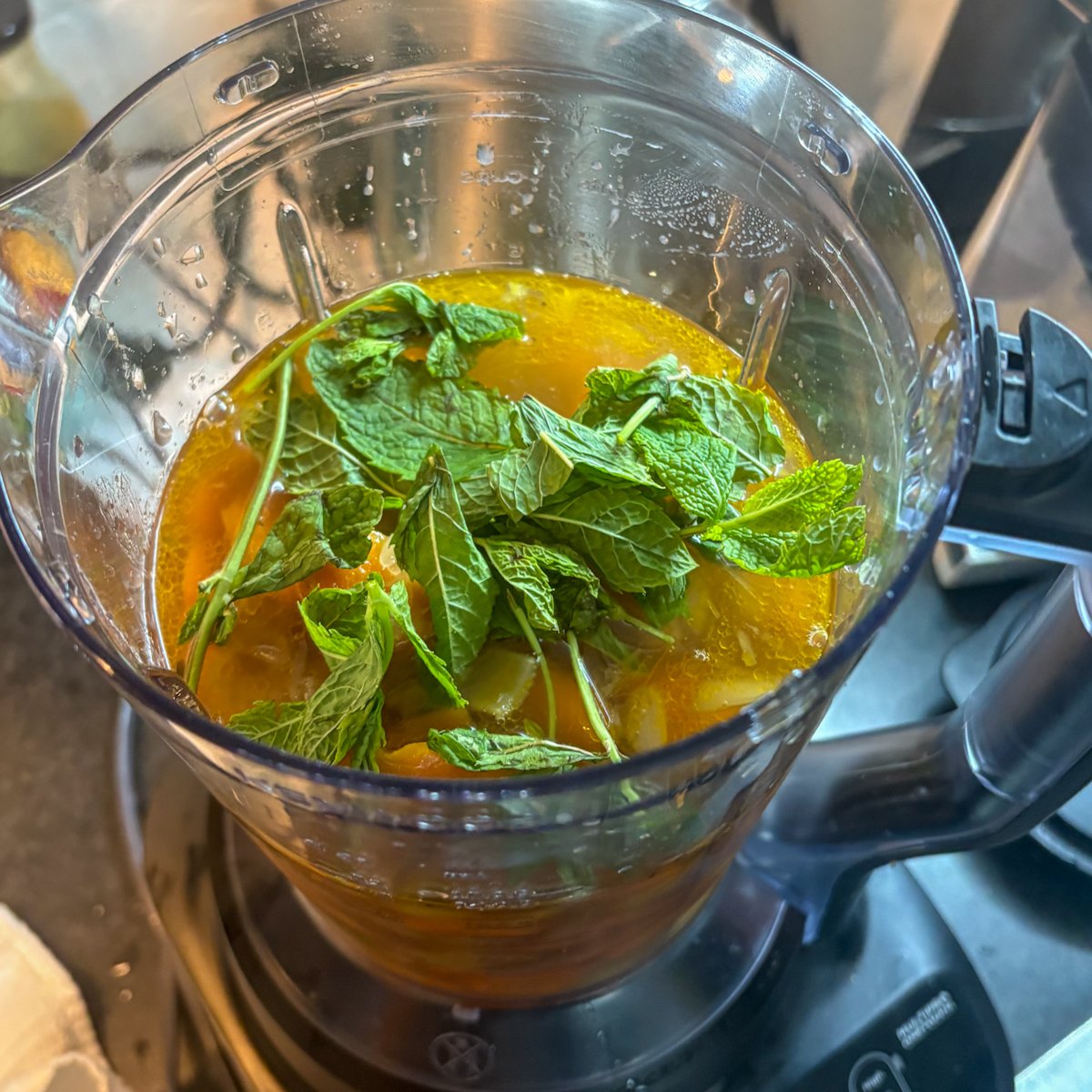 Fragrant chilled carrot soup base in a blender jug with cooked carrots, lime juice and fresh mint leaves on top.