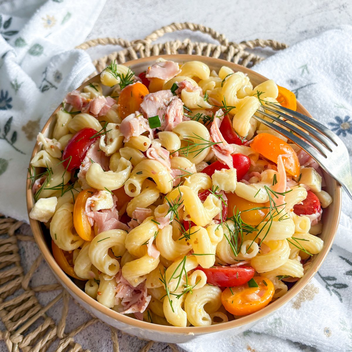 Colourful pasta salad with dill vinaigrette, full bowl topped with fresh dill