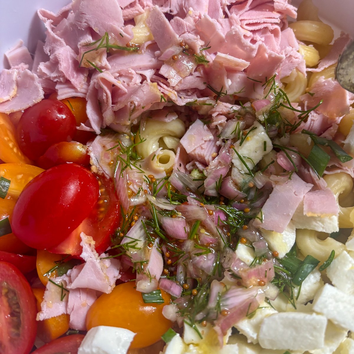 Ham, mozzarella and cherry tomatoes layered before mixing into pasta salad