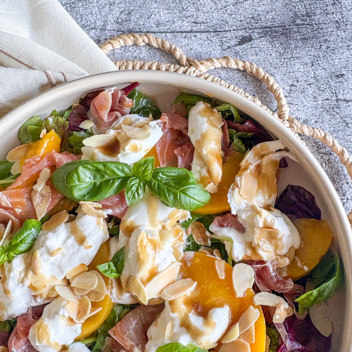  Peach and burrata salad close-up with torn burrata, peaches and ruffled prosciutto