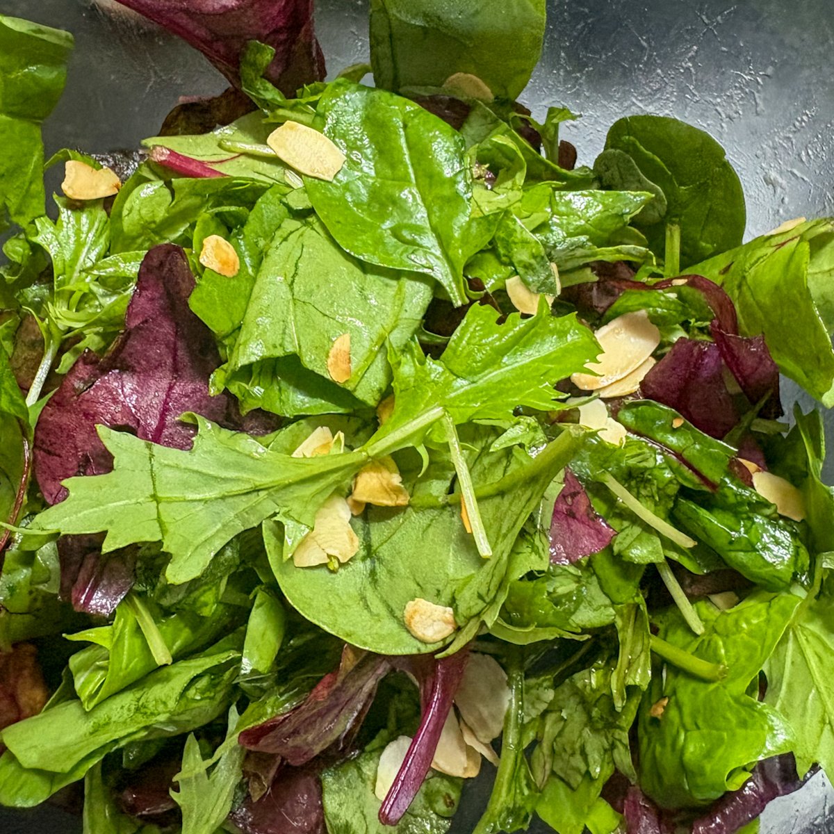 Dressed mixed leaves with flaked almonds for peach and burrata salad