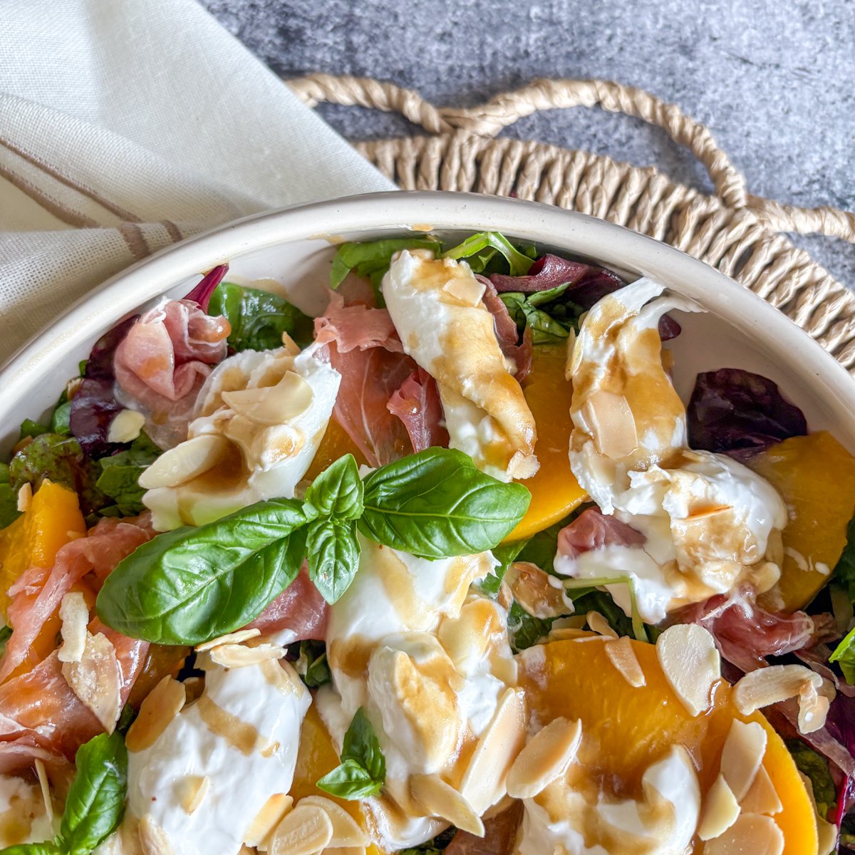 Peach and burrata salad close-up with creamy burrata, peach slices and prosciutto