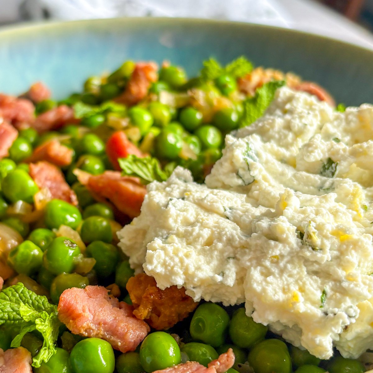 Peas with bacon and ricotta close-up — crisp bacon, green peas and minted ricotta