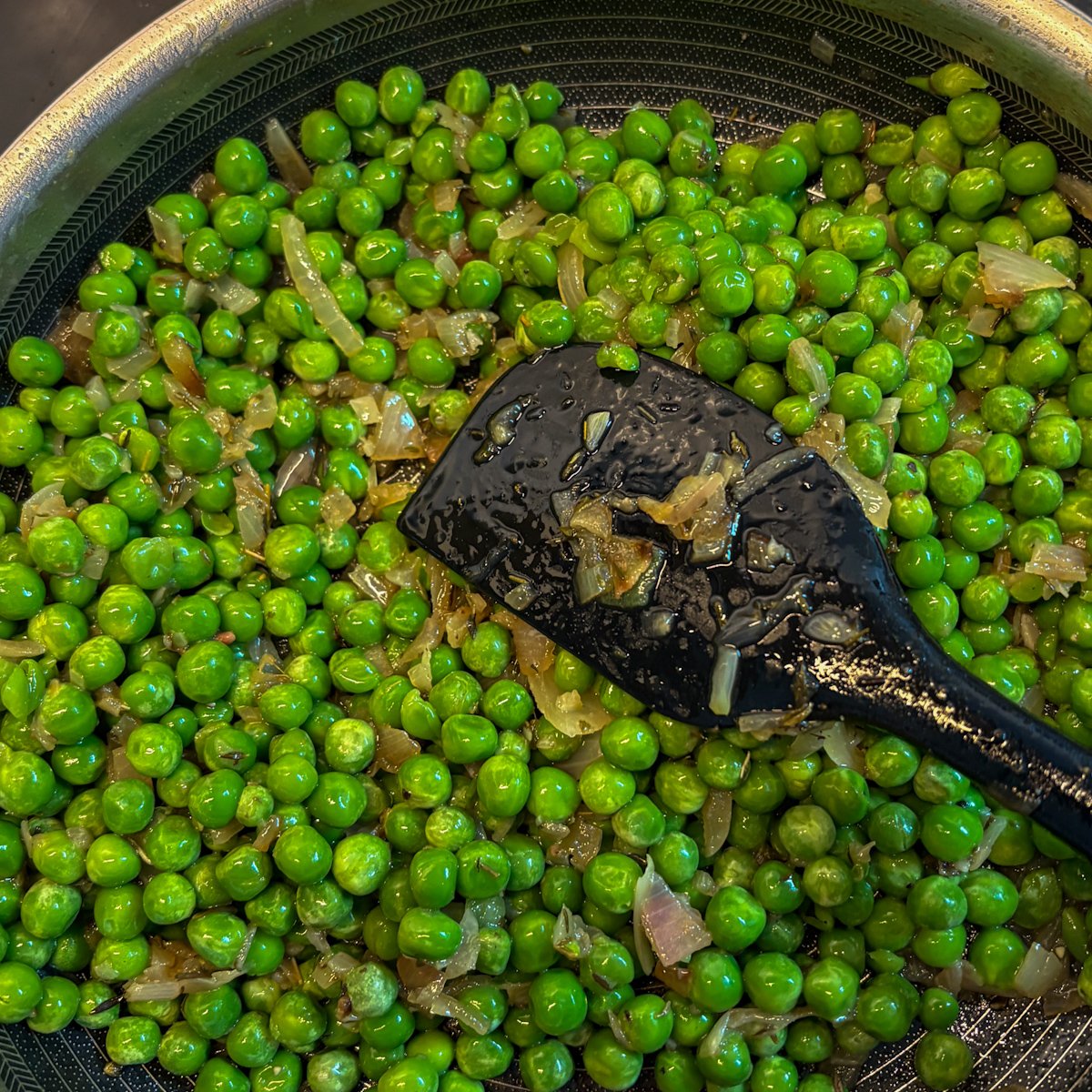 Emerald peas stirred into the pan — making peas with bacon and ricotta