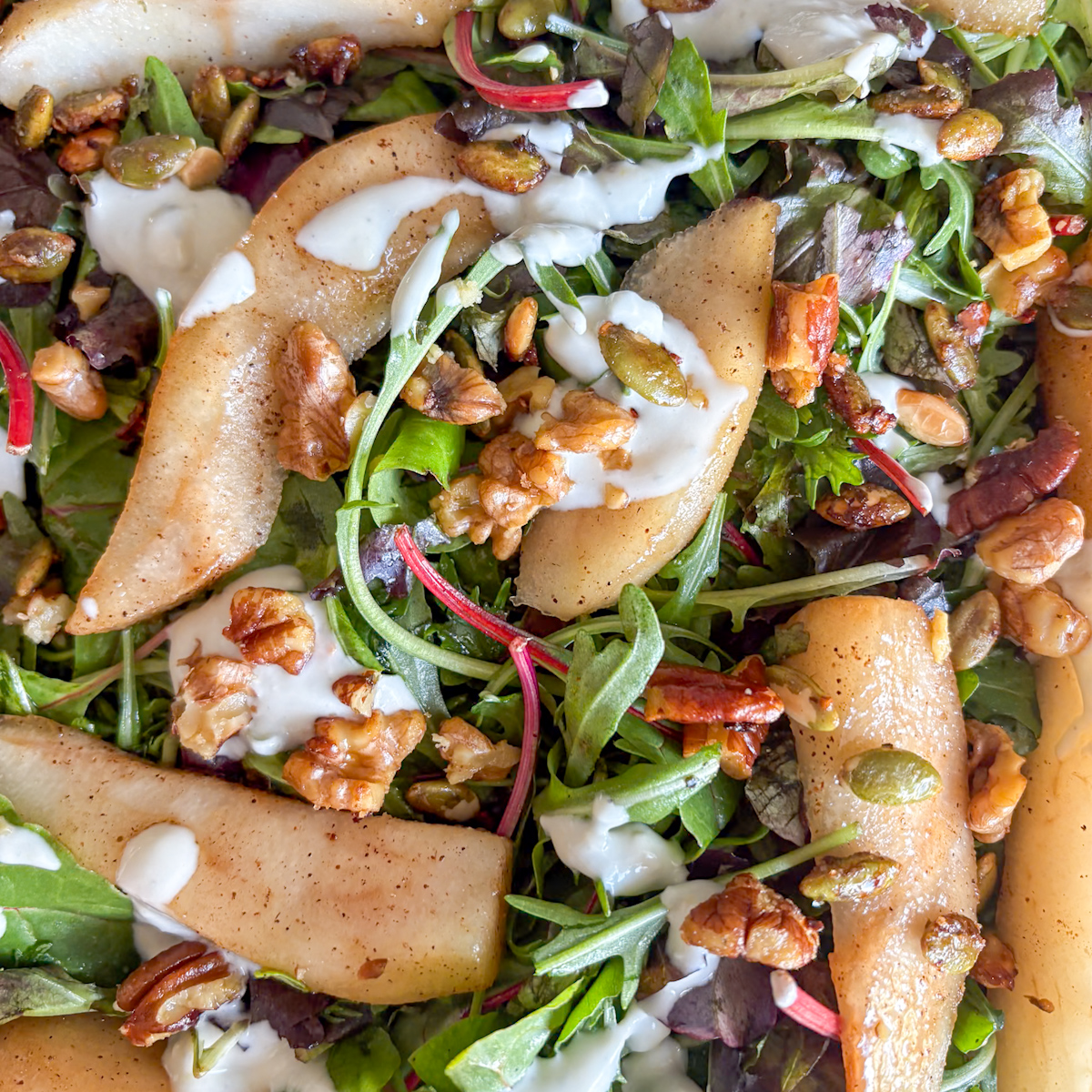 Close-up of poached pear salad with blue cheese dressing and candied nuts on green leaves