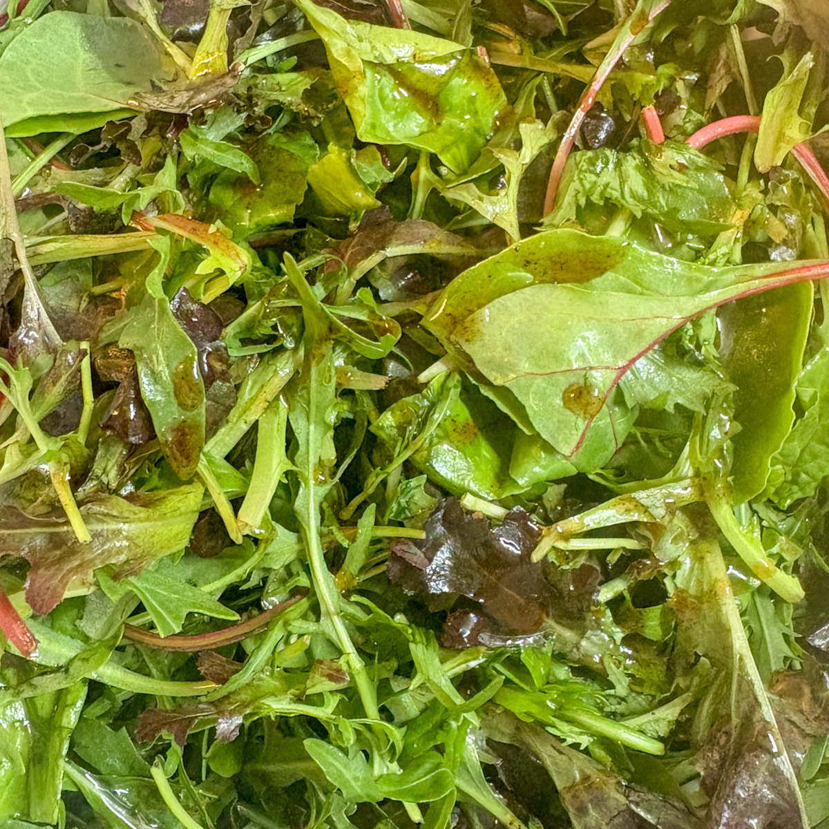 Mixed salad leaves dressed with olive oil and poaching liquid for poached pear salad