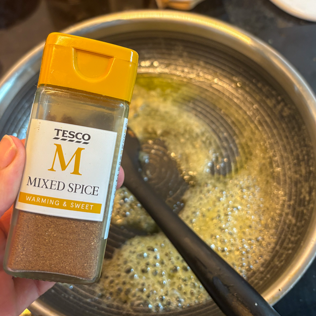 Mixed spice held over butter melting in a skillet for poached pear salad