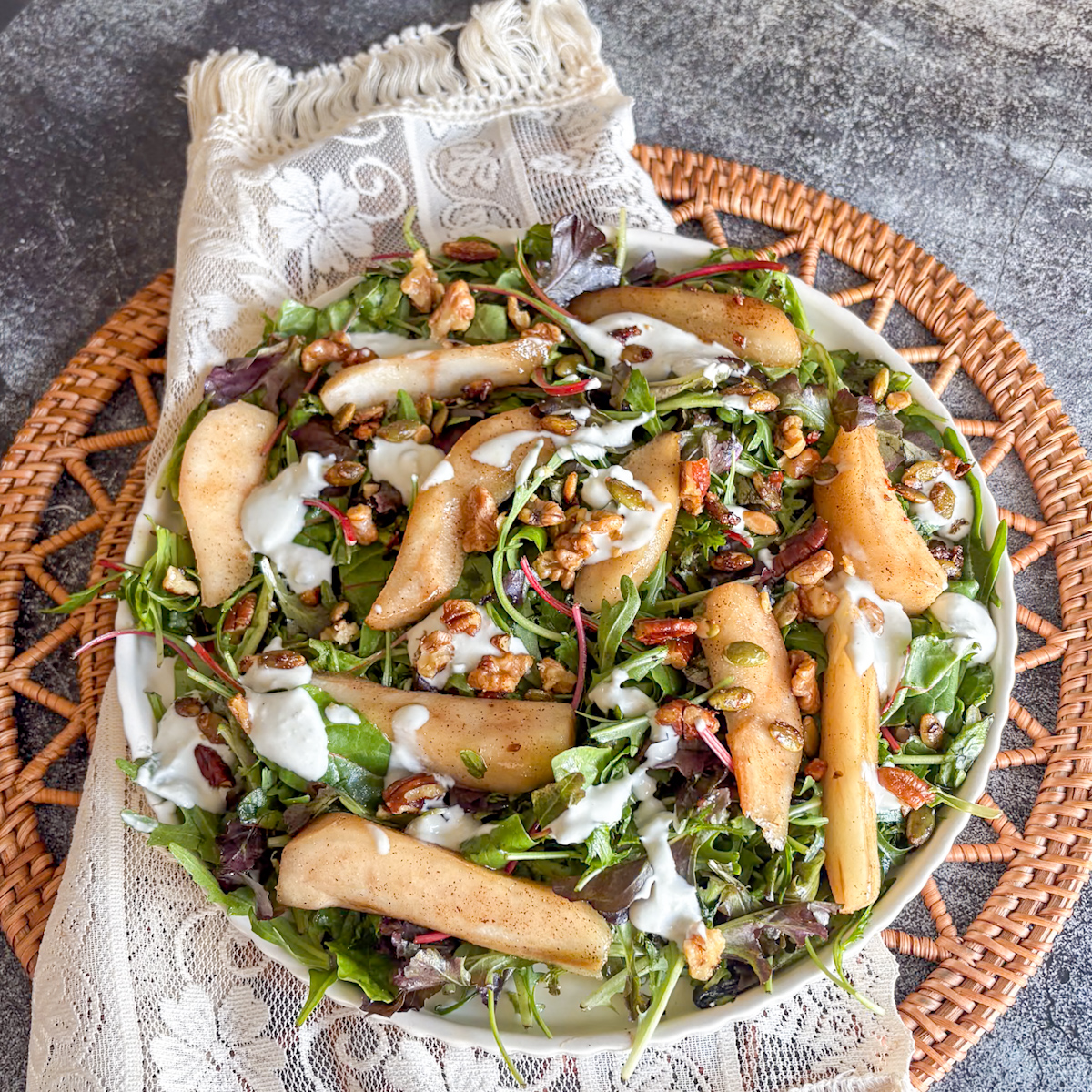 Poached pear salad with blue cheese dressing, pears and nuts scattered over leafy greens
