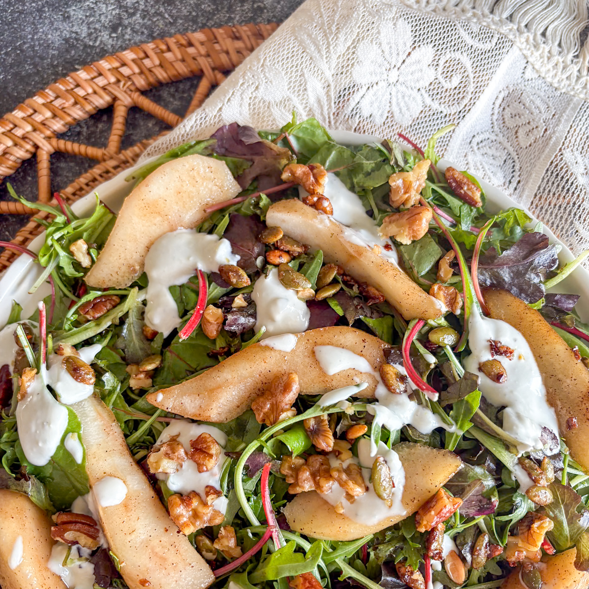 Poached pear salad with blue cheese dressing, pear wedges and pumpkin seeds on mixed leaves