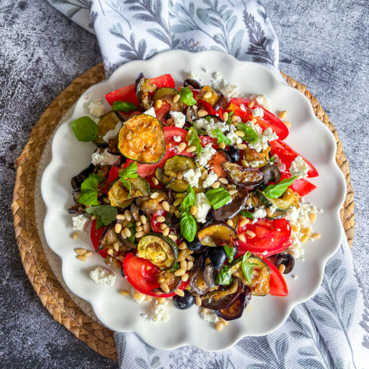 Healthy aubergine salad with roasted courgette, tomatoes, pine nuts and crumbled feta