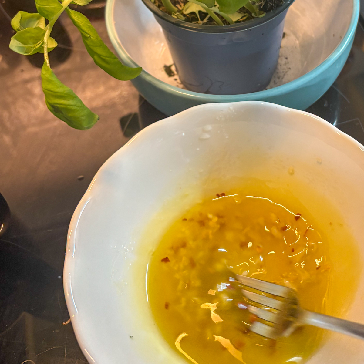  Lemon dressing for roasted courgette and aubergine salad whisked in a white bowl with garlic and chilli