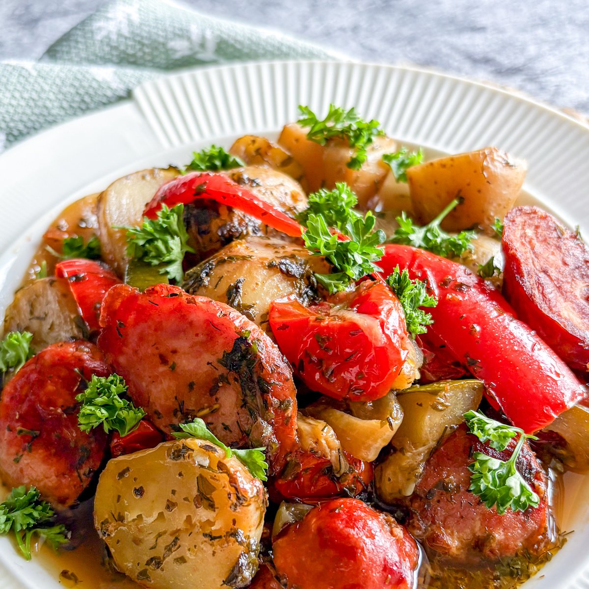 Angled close-up of smoked sausage and potato stew with peppers, courgette and parsley